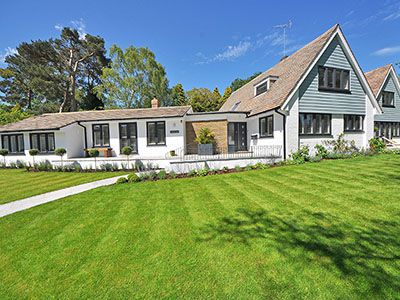 Large white house with landscaped yard and striped lawn.