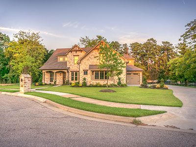 Two-story brick home at sunset with landscaping and manicured yard.