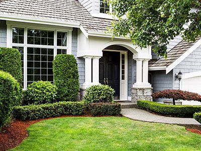 Home with light blue siding, mulched landscaping with assorted manicured
              bushes and tidy lawn.