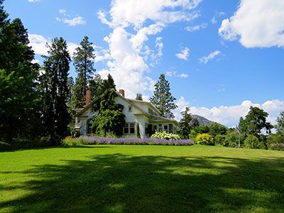 White, two-story home with large mowed lawn and lots of floral landscaping.